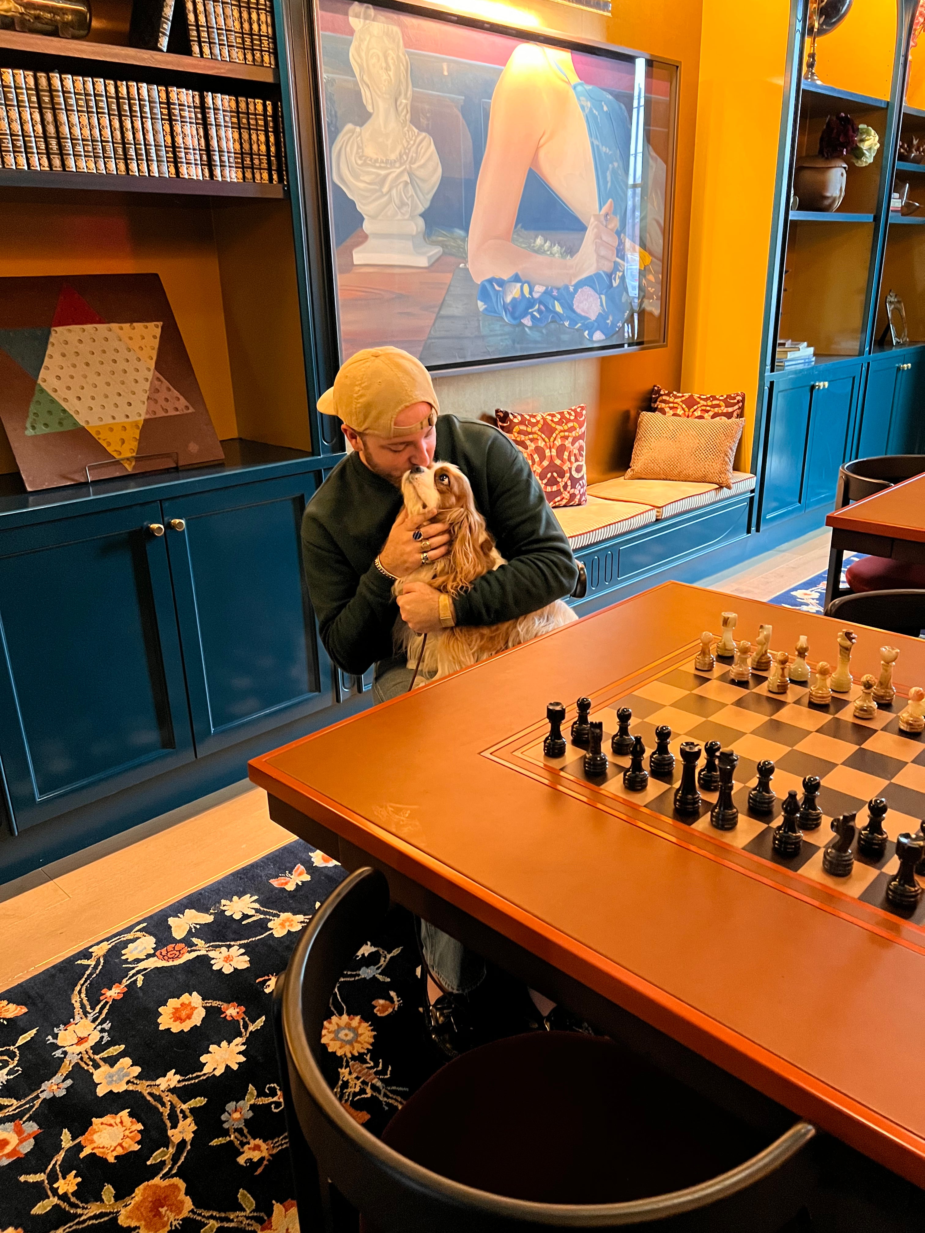 Person holding a dog in a room with a chessboard on a table